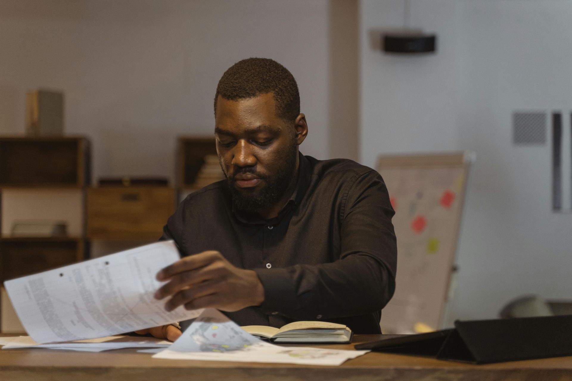 "A professional grant writer reviewing funding proposals and conducting in-depth grant research. The workspace includes financial documents, a notebook, and a strategic planning board in the background, emphasizing business funding and nonprofit grant development."